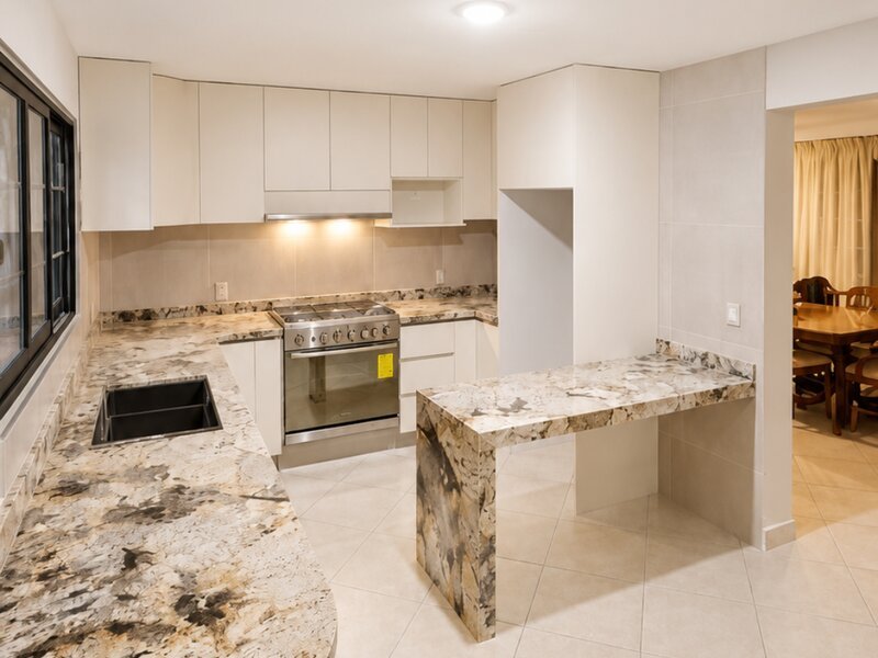 Cocina integral con isla y barra de granito instalada por Lia Cucina